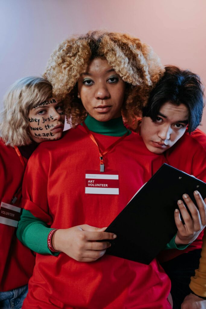 Portrait of diverse volunteers wearing red shirts and engaging in art activities.